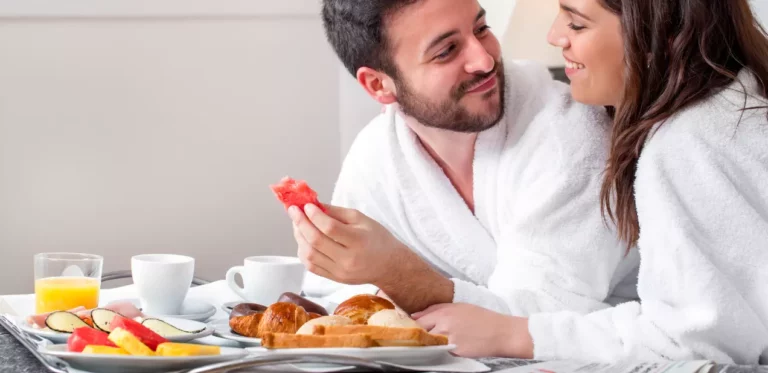 Landhotel Classhof Ehepaar bei Frühstück im Bett nach Hochzeit im Hotel. Mann und Frau genießen Frühstück mit Obst Brot Kaffee und Saft